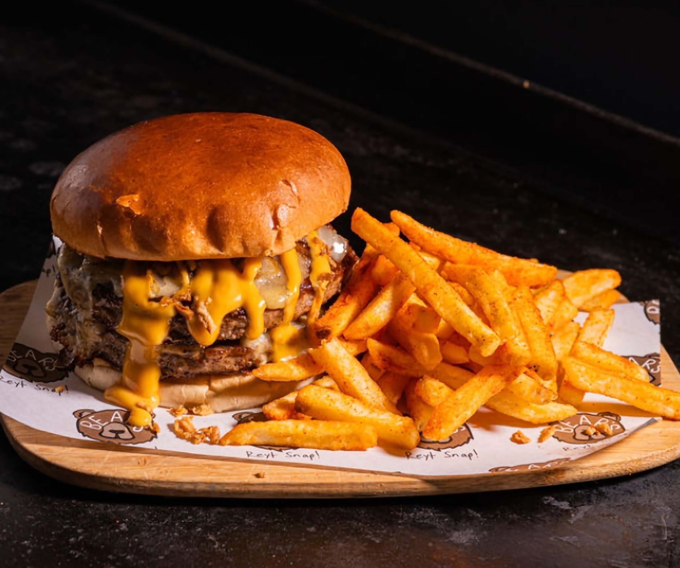 A massive Bears gourmet double cheeseburger on a brioche bun with melting cheese and fries, showcasing the fresh-prep alternative to lukewarm boxed crew meals.