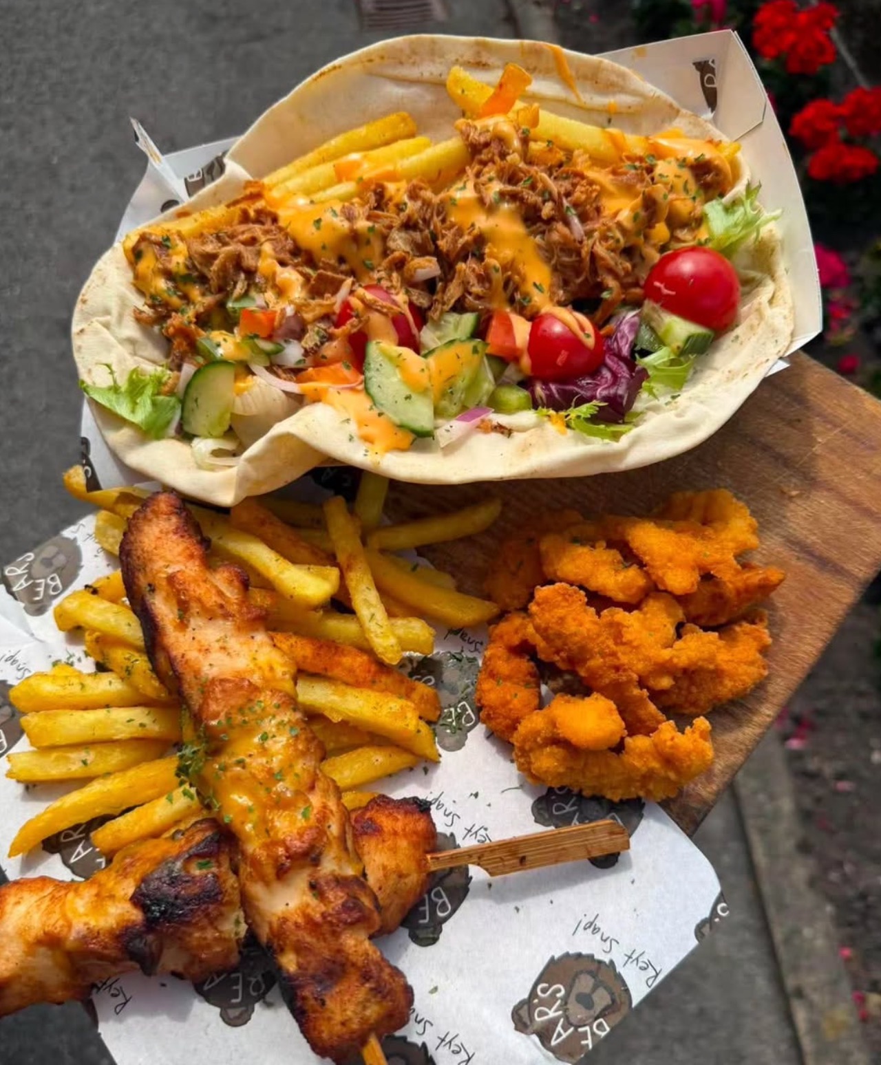 A wooden serving board featuring freshly grilled chicken skewers, seasoned fries and crispy chicken pieces for high-protein TV & film catering.