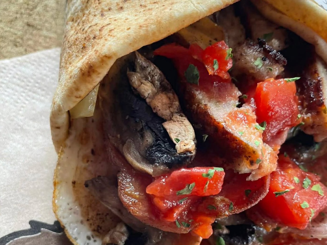 A fresh flame-grilled flatbread wrap filled with savoury meats, herbs and diced tomatoes for remote TV & film catering.