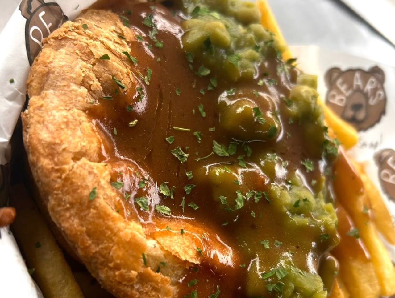 An artisan pie smothered in rich gravy and served with mushy peas for workplace canteen catering.
