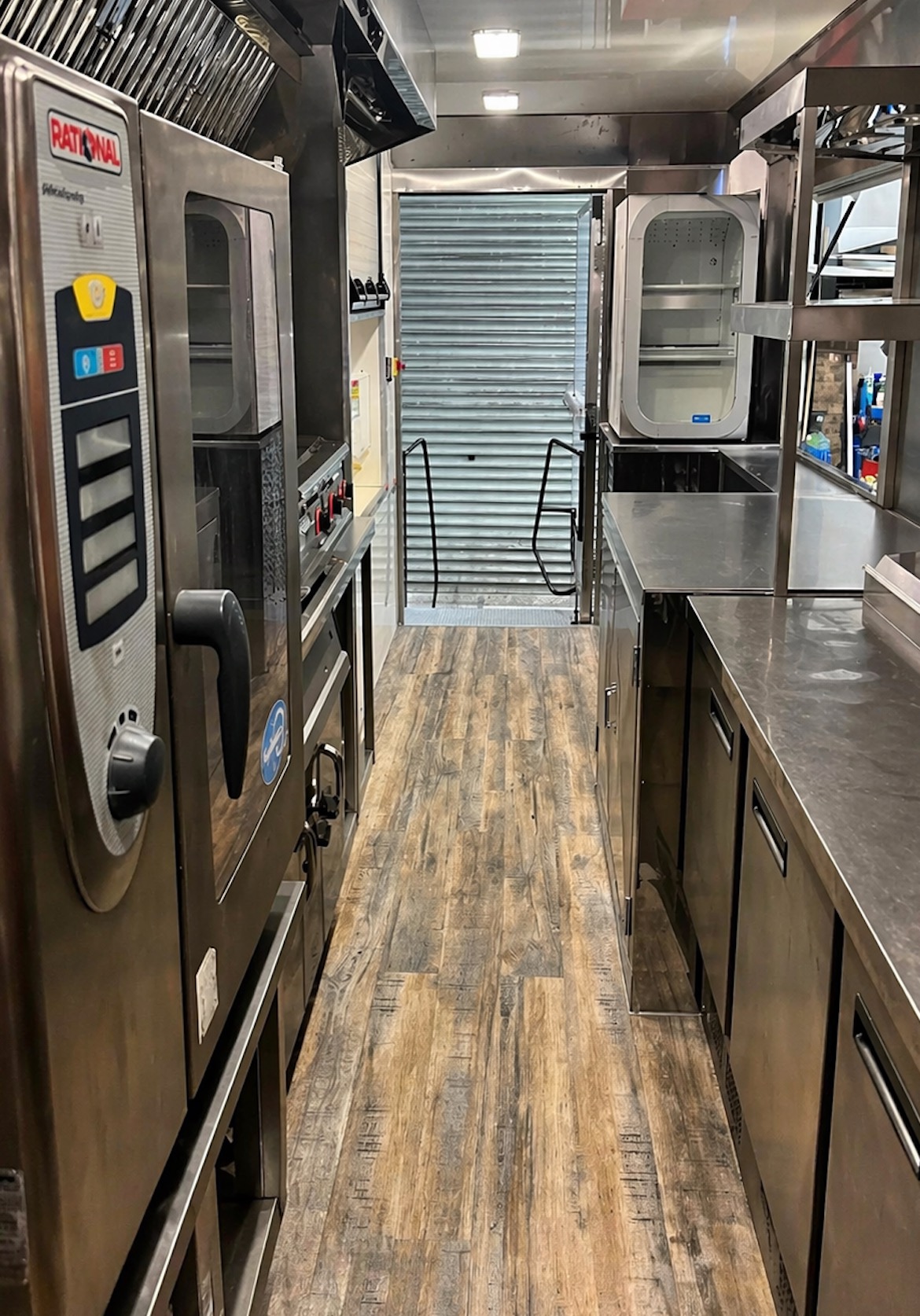 An interior view of a clean, high-spec mobile catering unit featuring stainless-steel prep counters and commercial Rational ovens, designed for sustainable workplace canteen catering.